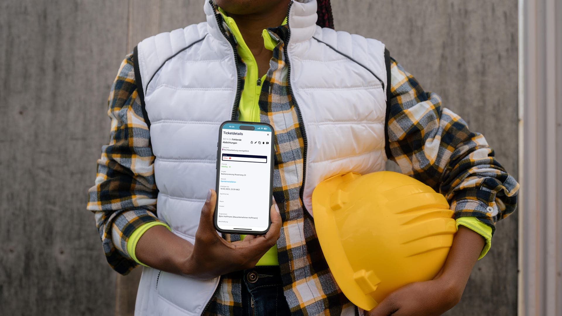 Bauarbeiterin hält Handy mit Ticketverwaltung von Flexxter in der Hand