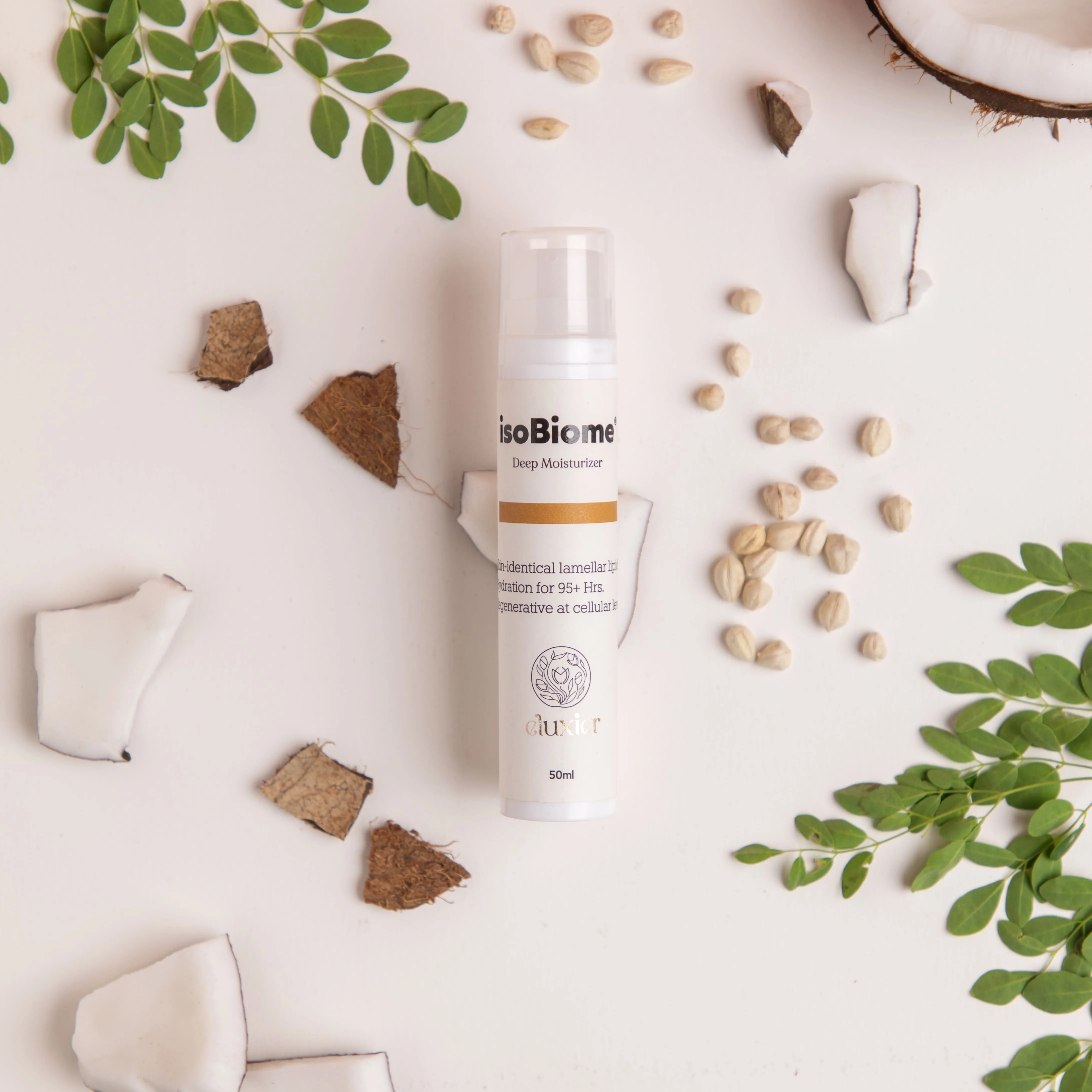 Bottle of isoBiome Deep Moisturizer surrounded by coconut pieces, seeds, and green leaves on a light surface.