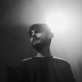 Black and white portrait of a young man looking to the side with bright light behind his head.