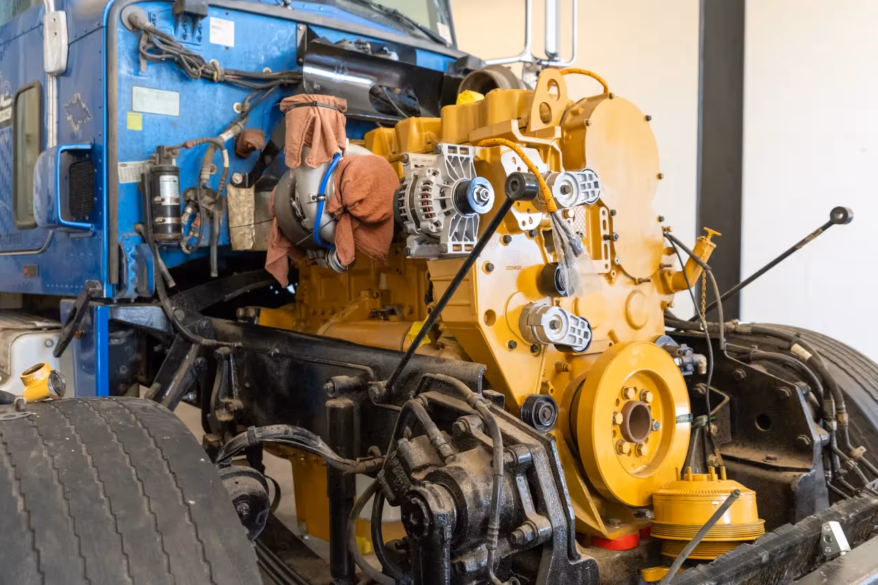 Preventive maintenance on a truck engine with components exposed for inspection and service in a repair bay.