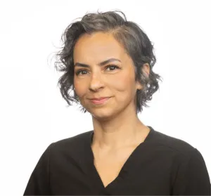 Portrait of a woman with short curly hair wearing a black top and smiling slightly.
