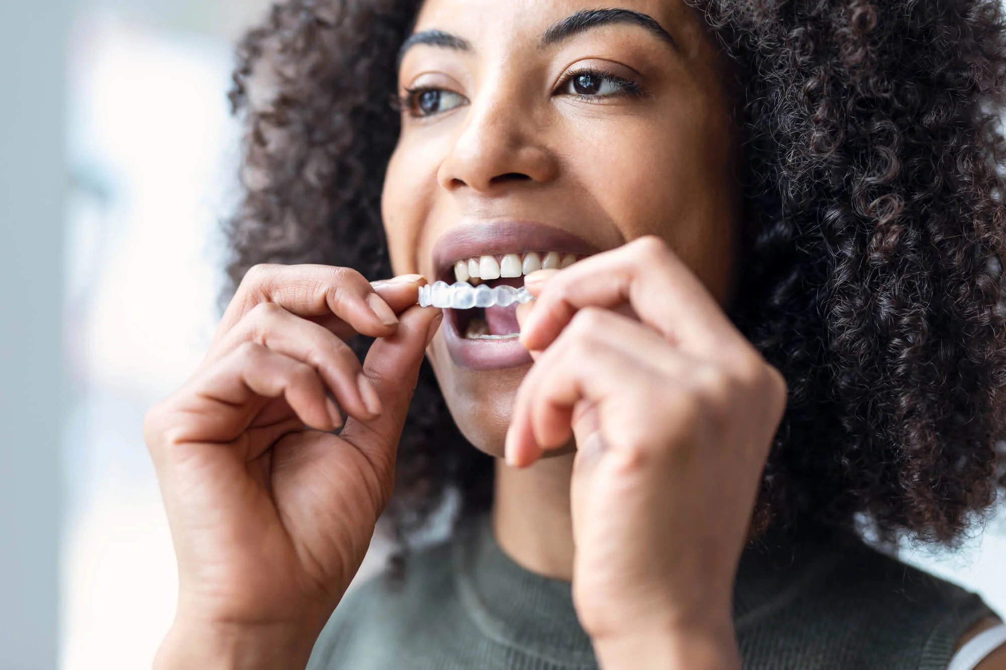 Woman placing clear aligners for Dallas, TX Invisalign.