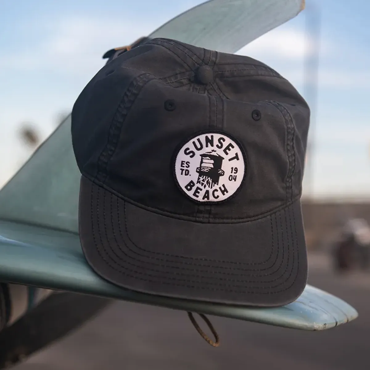 Sunset Beach water tower patch hat on surfboard fin.