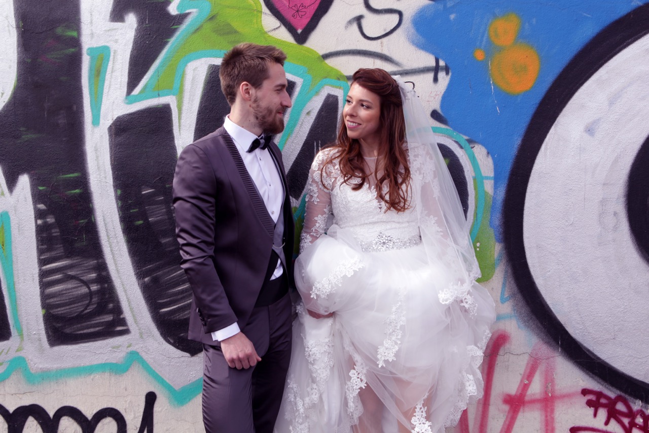 A young bride and groom standing on front of a colorful graffiti wall