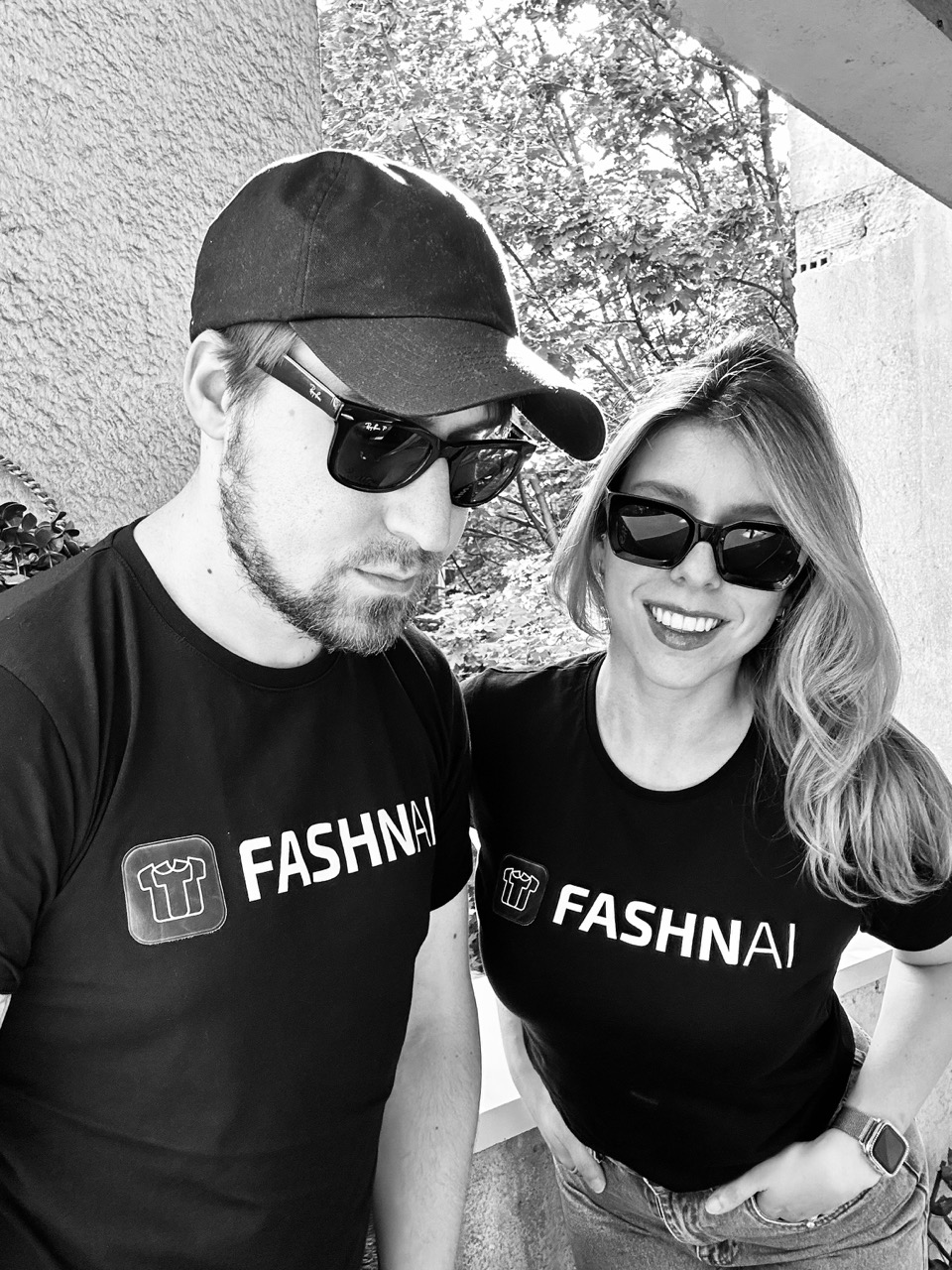 A black and white photo of a man and woman wearing t-shirts that say FASHN.AI