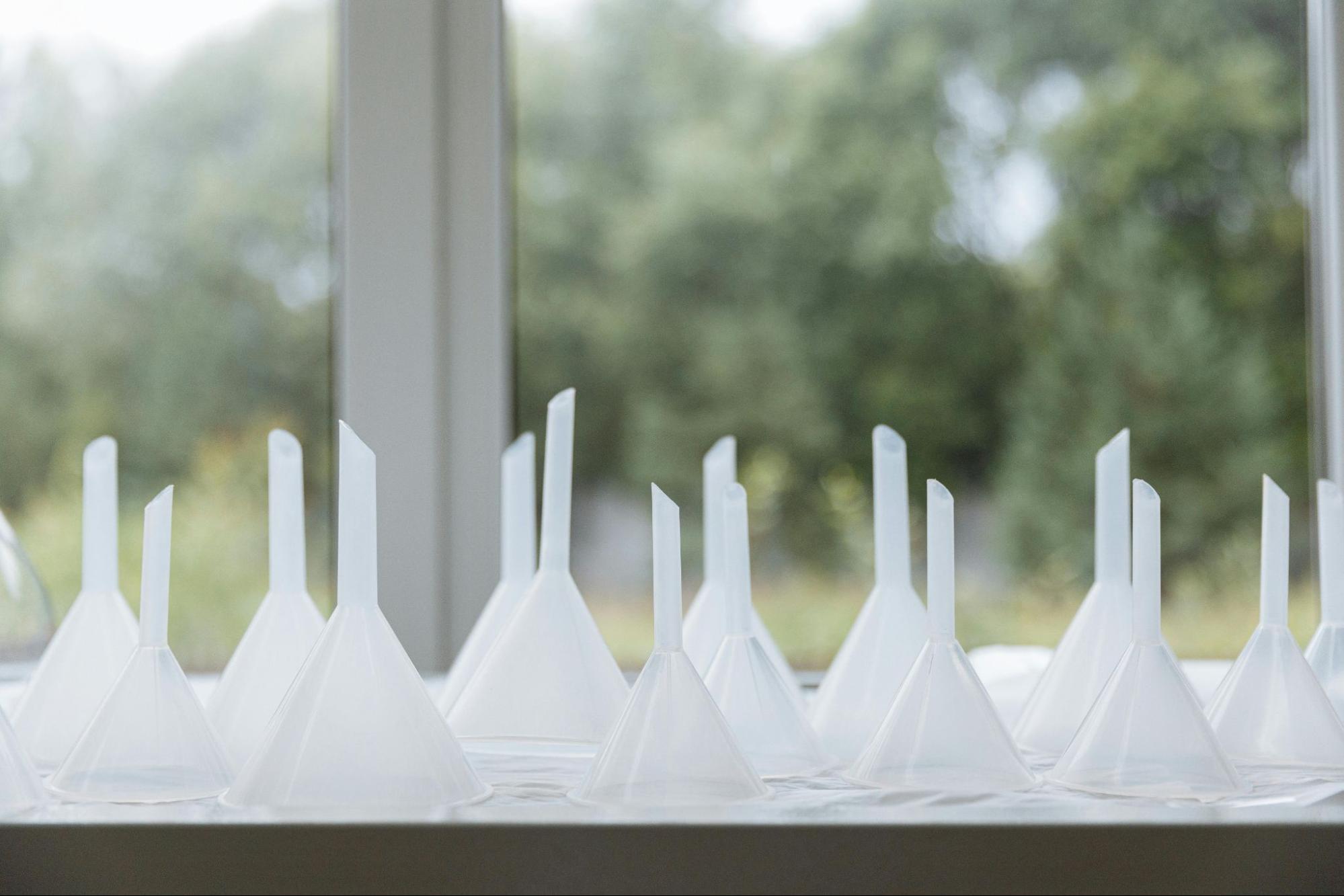 Multiple transparent plastic funnels arranged near a window, visually representing the concept of conversion funnels in marketing