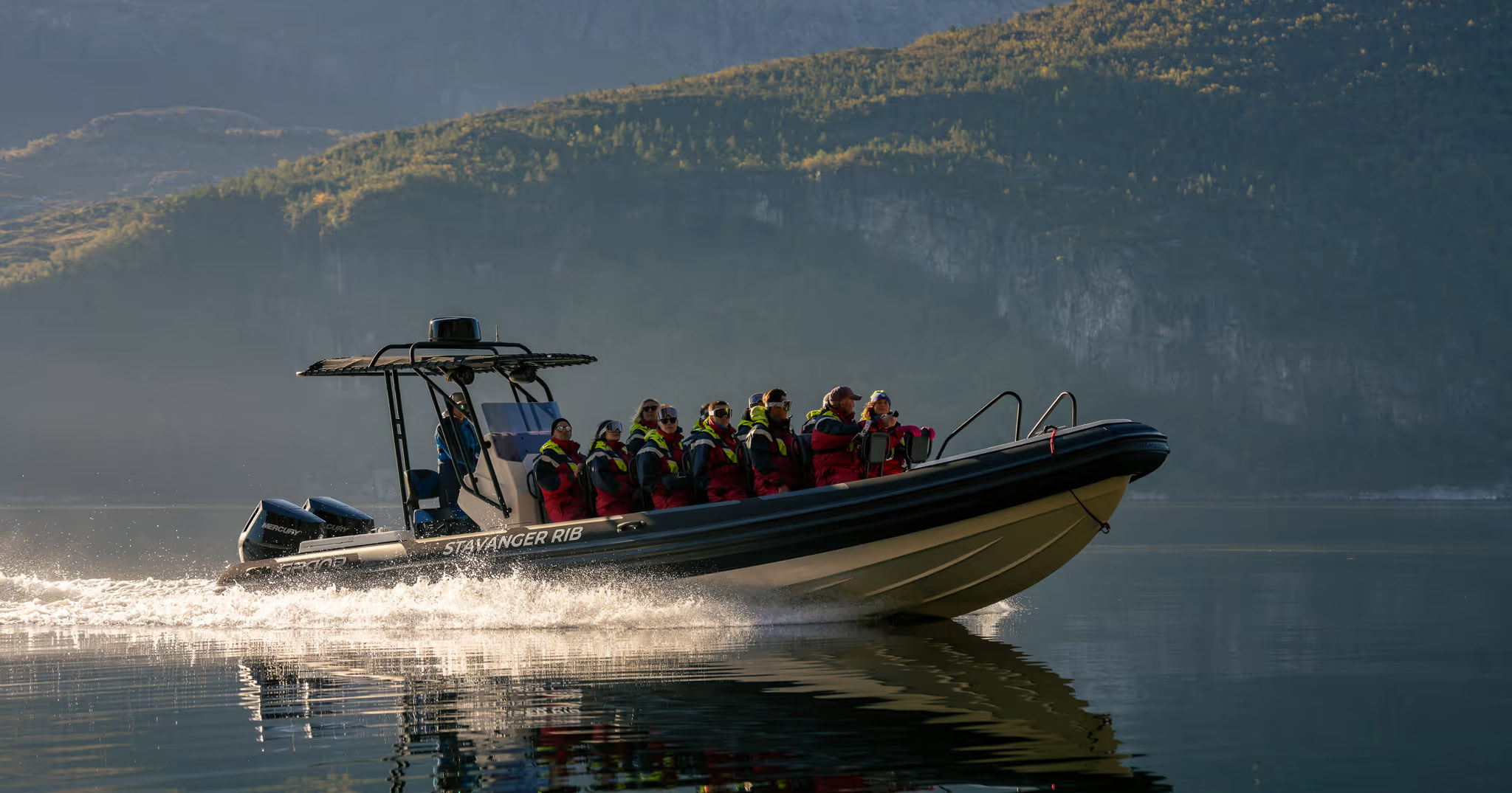Tourists enjoying a RIB boat tour on a calm fjord near Stavanger, with scenic mountains in the background.