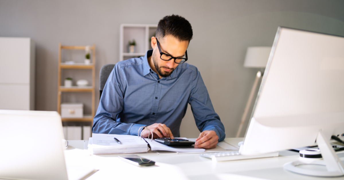Finance professional reviewing invoices and calculating expenses at a desk, symbolising automated accounts payable workflows, global payment accuracy, and fraud prevention best practices.