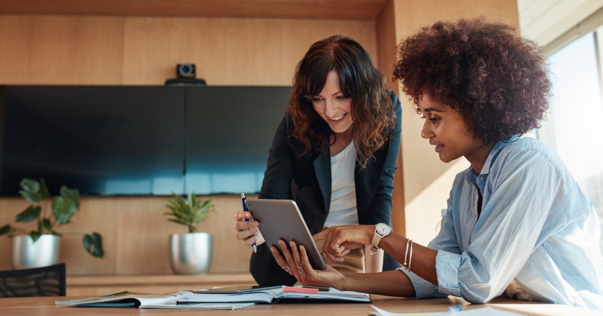 Coworkers reviewing employee expense reimbursement guidelines together on a laptop