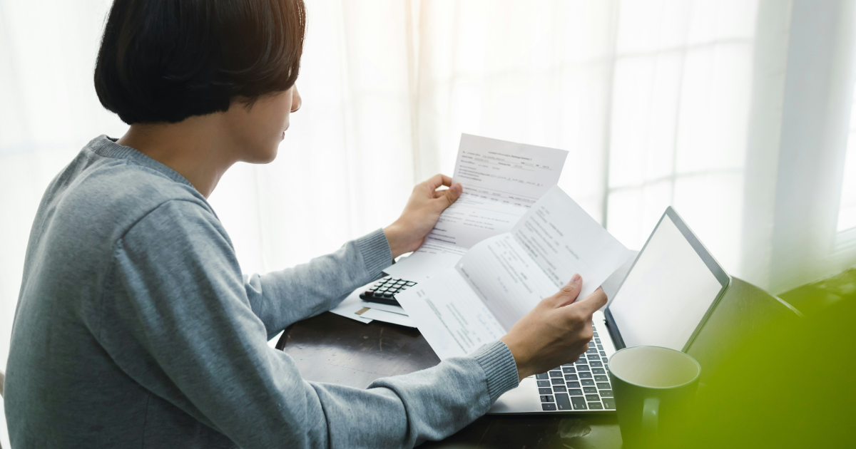 Finance team member manually reviewing paper invoices and bills at a desk, the manual process invoice management software replaces
