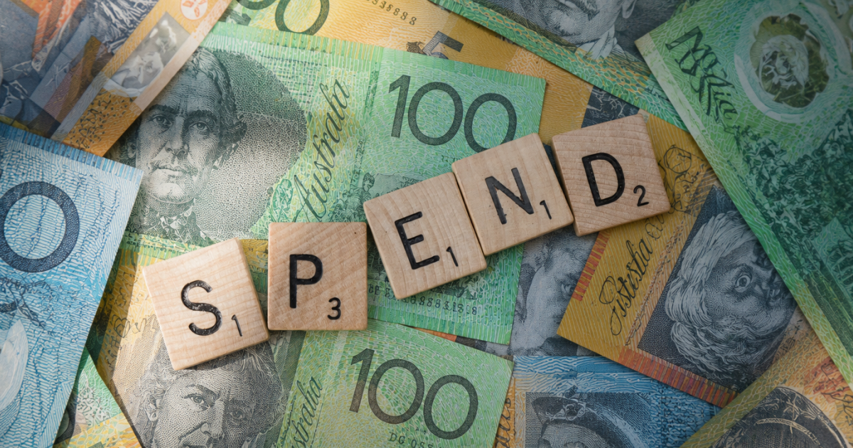 Wooden letter tiles spelling SPEND over Australian dollar banknotes, representing expense claim and reimbursement spend