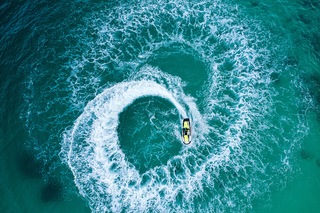 Jet ski vu du ciel traçant des cercles dans une eau turquoise aux Caraïbes