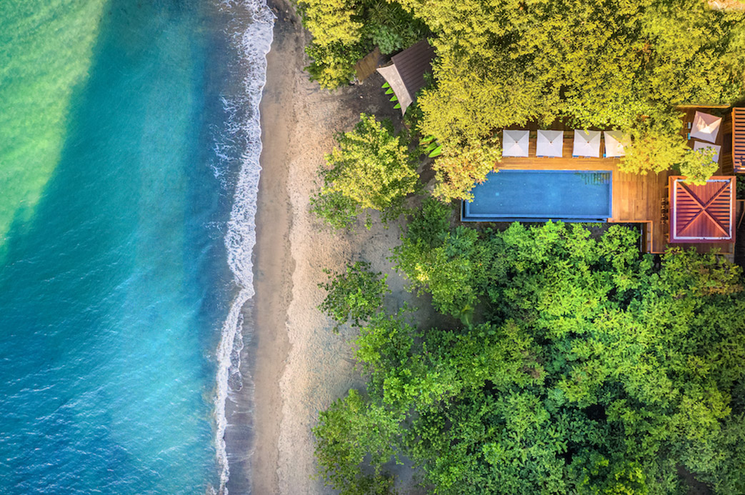 Vue aérienne d’une villa de luxe avec piscine privée entourée de forêt tropicale en bord de plage à la Dominique