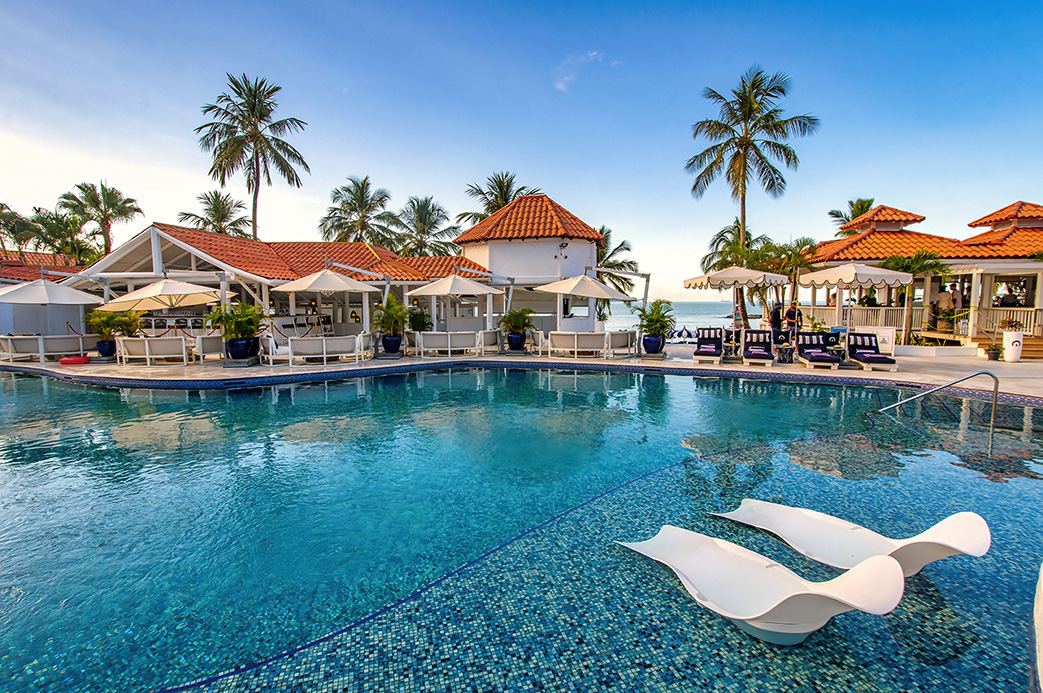 Piscine d’un resort de luxe à Sainte-Lucie avec transats, parasols et vue sur la mer des Caraïbes
