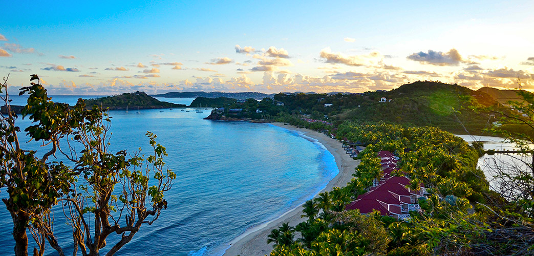 Coucher de soleil sur une plage bordée de palmiers à Antigua avec vue panoramique sur la baie des Caraïbes