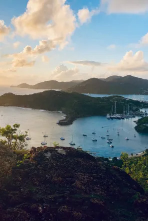 Vue panoramique d'Antigua depuis le sommet d'une colline sur la baie en contrebas, avec des eaux scintillantes et un ciel dégagé.