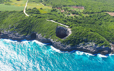 Perspective aérienne d'une grotte côtière, illustrant la rencontre entre la terre et la mer dans un cadre naturel.
