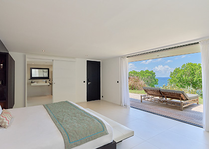 Grande chambre de la Villa Ayati ouverte sur une terrasse en bois avec transats et vue mer en Guadeloupe