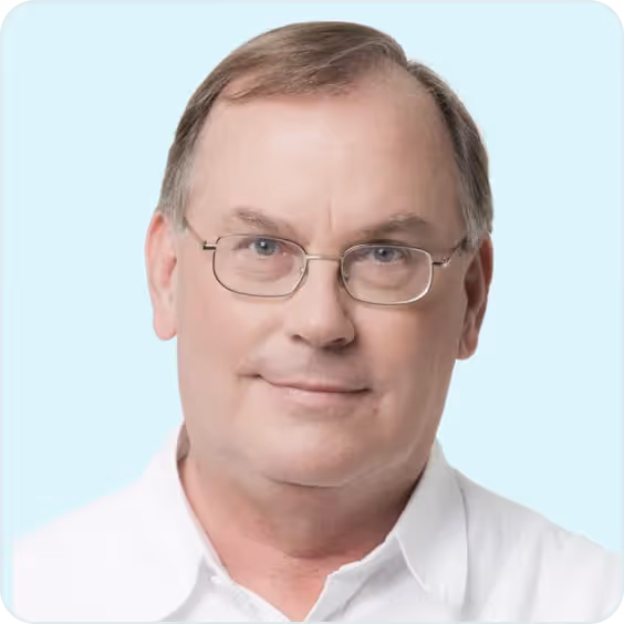 Professional headshot of Ed Michael, Board Member at PatientPartner, wearing glasses and a white shirt against a light blue background