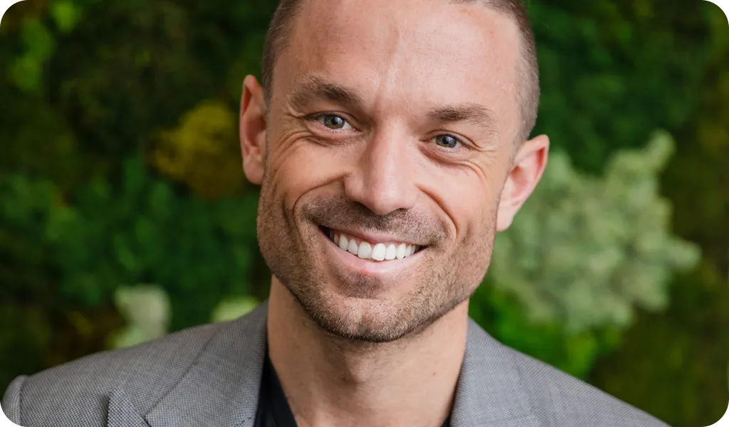 Patrick Frank, COO and Co-Partner at PatientPartner, smiling in front of a green background.