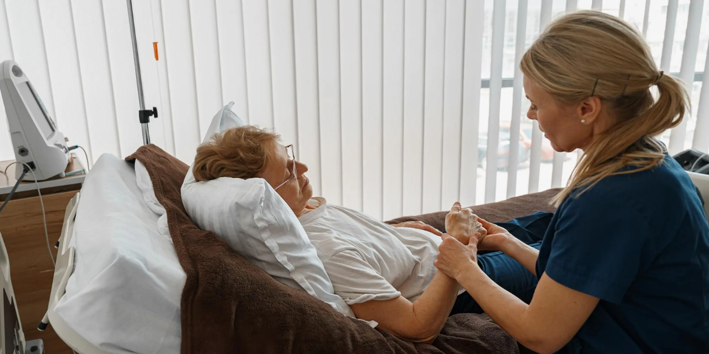 Nurse supporting elderly patient in hospital using patient engagement software for compassionate care.