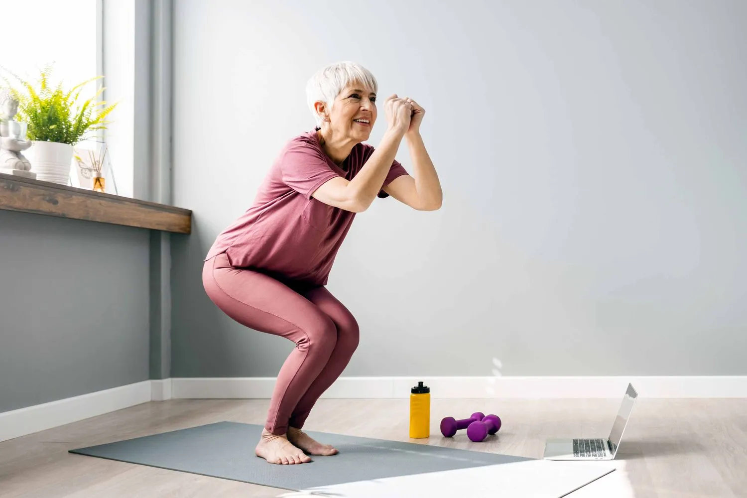 Older woman stretching on a yoga mat at home, healthy aging with longevity medicine in Los Gatos