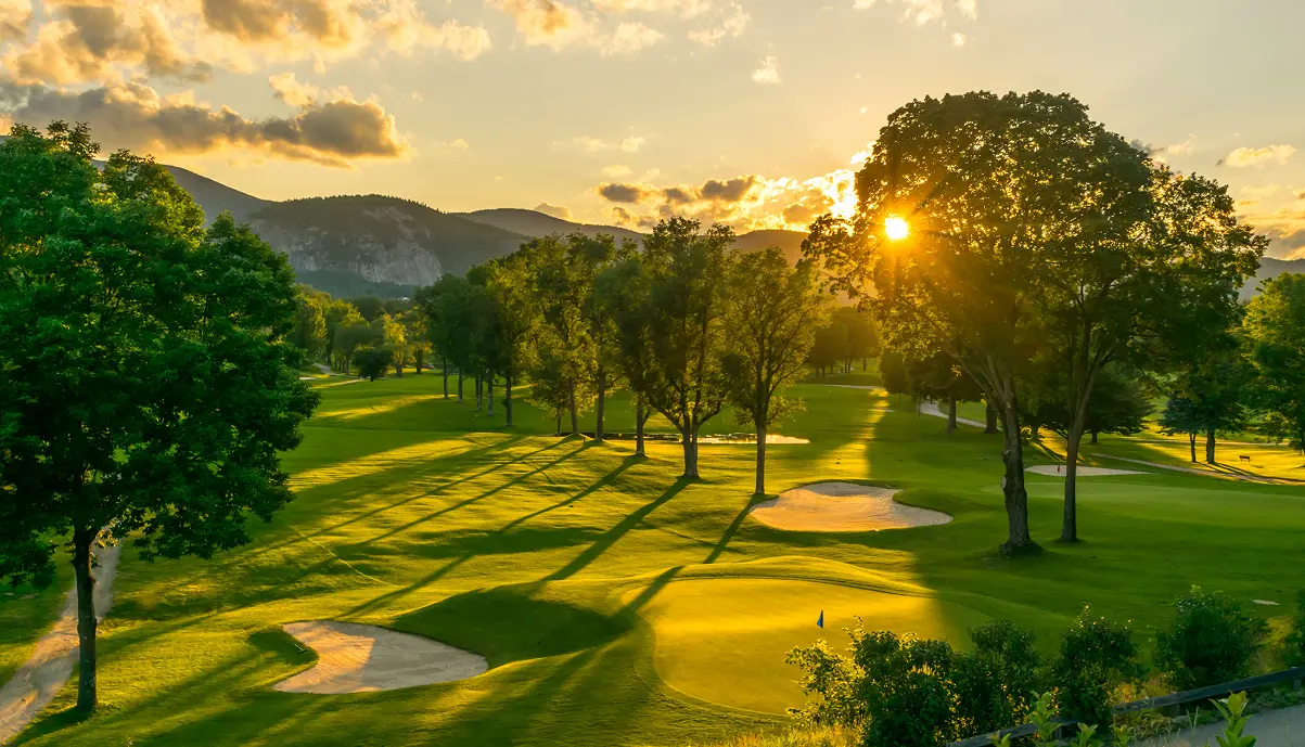 Panoramic view of a golf course at sunset with golfer