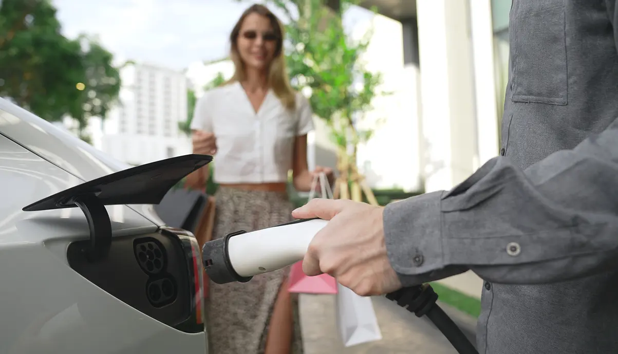 Client d'hôtel branchant son véhicule électrique sur une borne de recharge Qovoltis