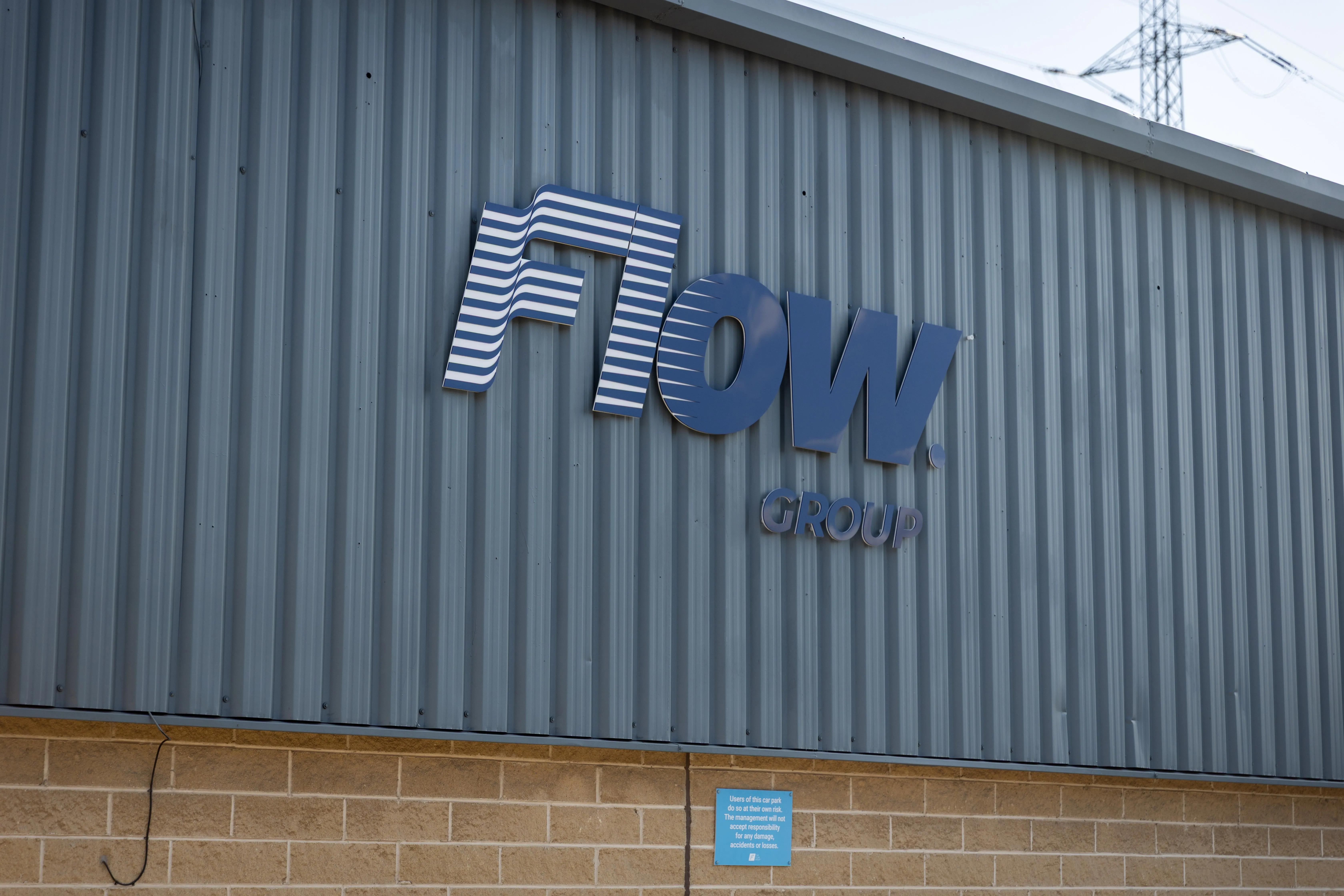 A close-up view of the Flow Group brand sign mounted on the exterior of the company’s premises, clearly displaying the logo and branding elements