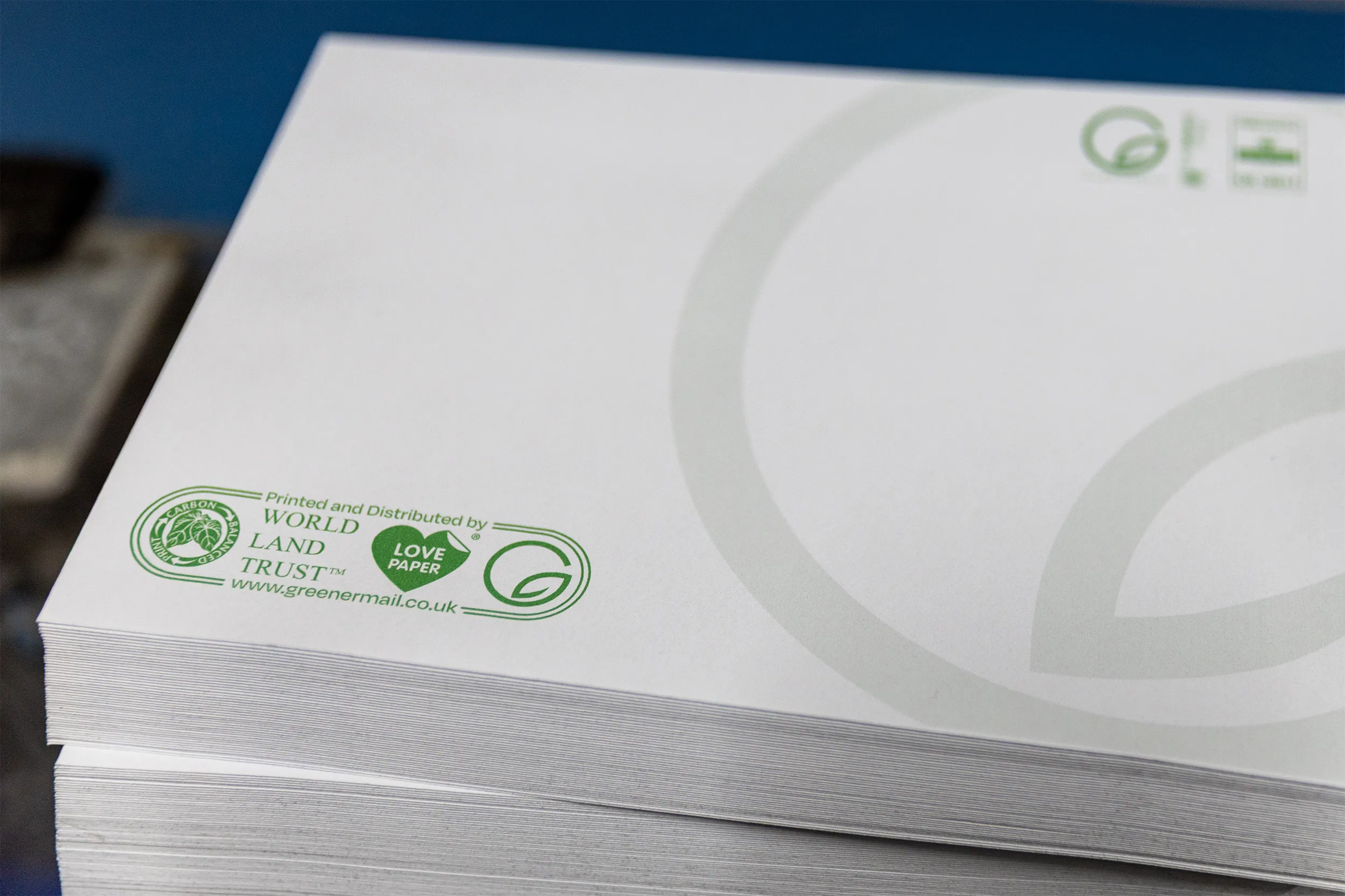 Stack of white paper with green logos and text indicating it is printed and distributed by World Land Trust using Love Paper.