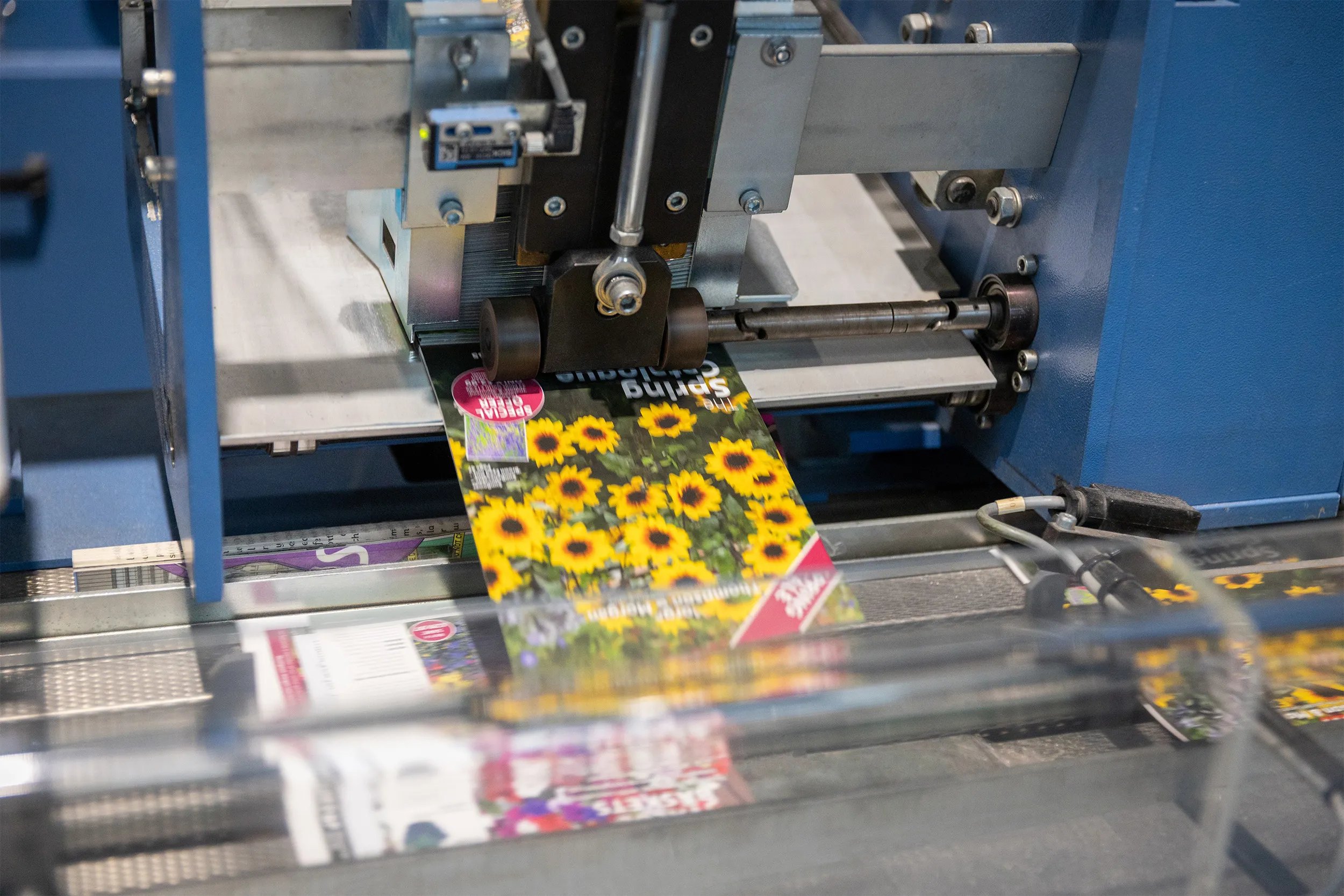Printing machine producing color magazine pages with sunflower images.