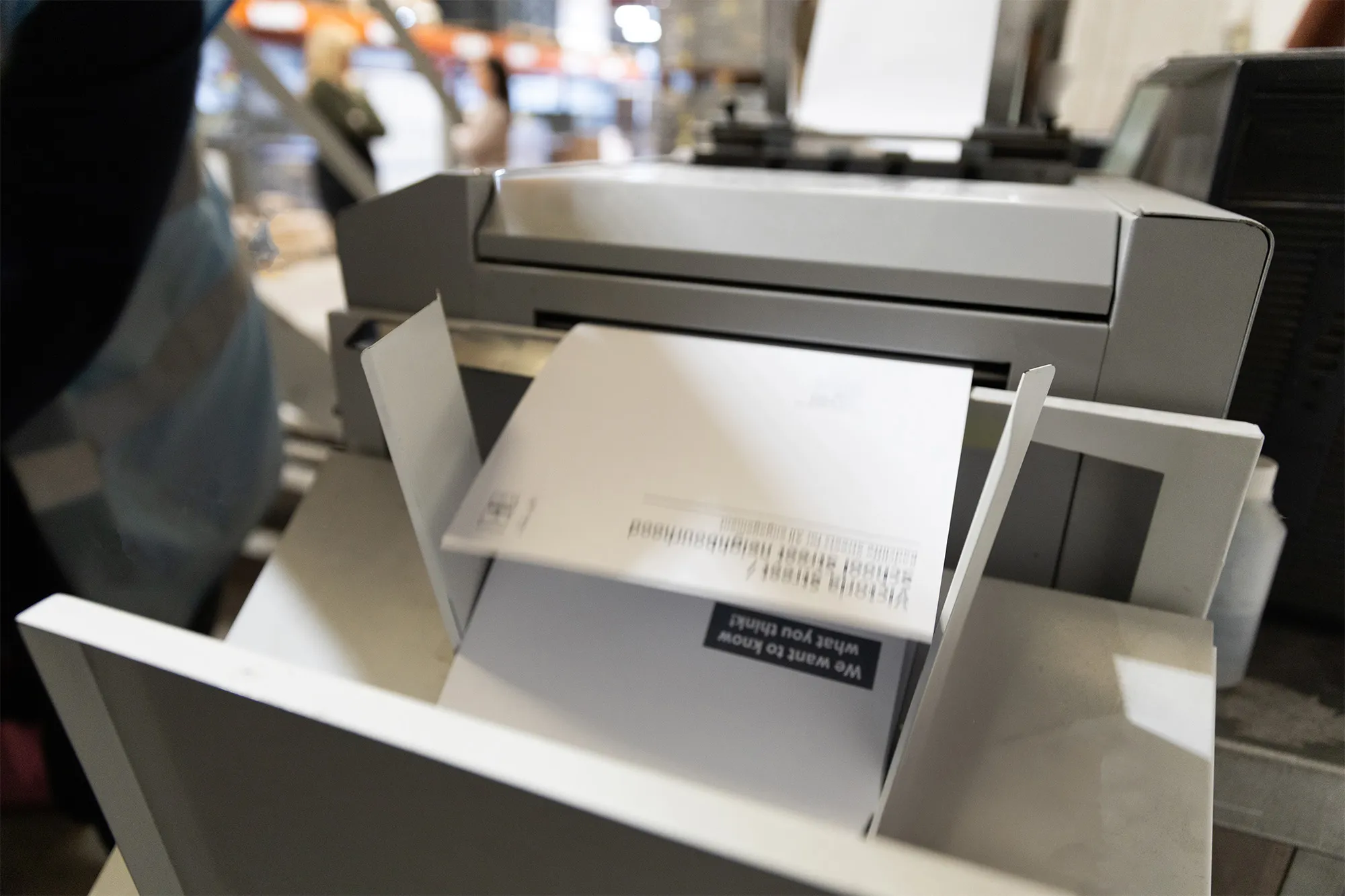 Close-up of an industrial printer outputting printed sheets into a collection tray.