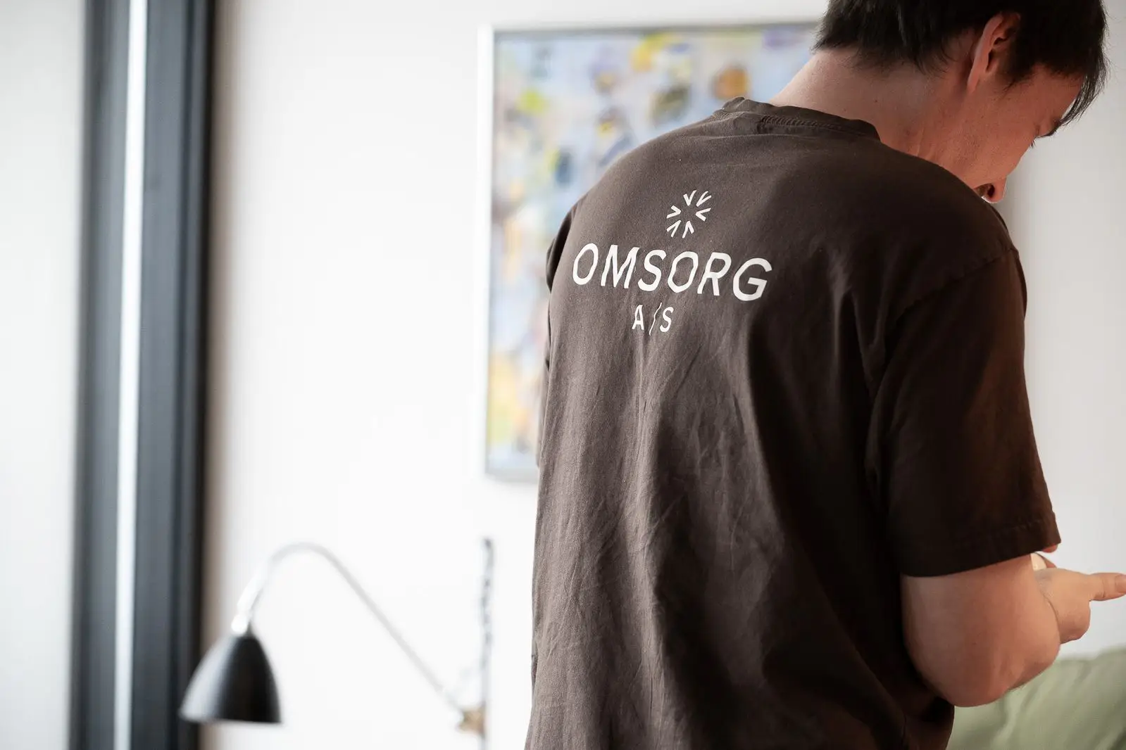 en medarbejder står med ryggen til, med omsorg a/s logo på ryggen af hans t-shirt