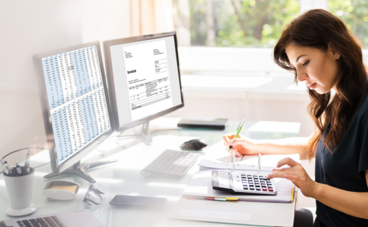 Working at desk with invoices open in background