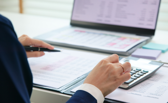 Image of hands while working on sheets with a calculator