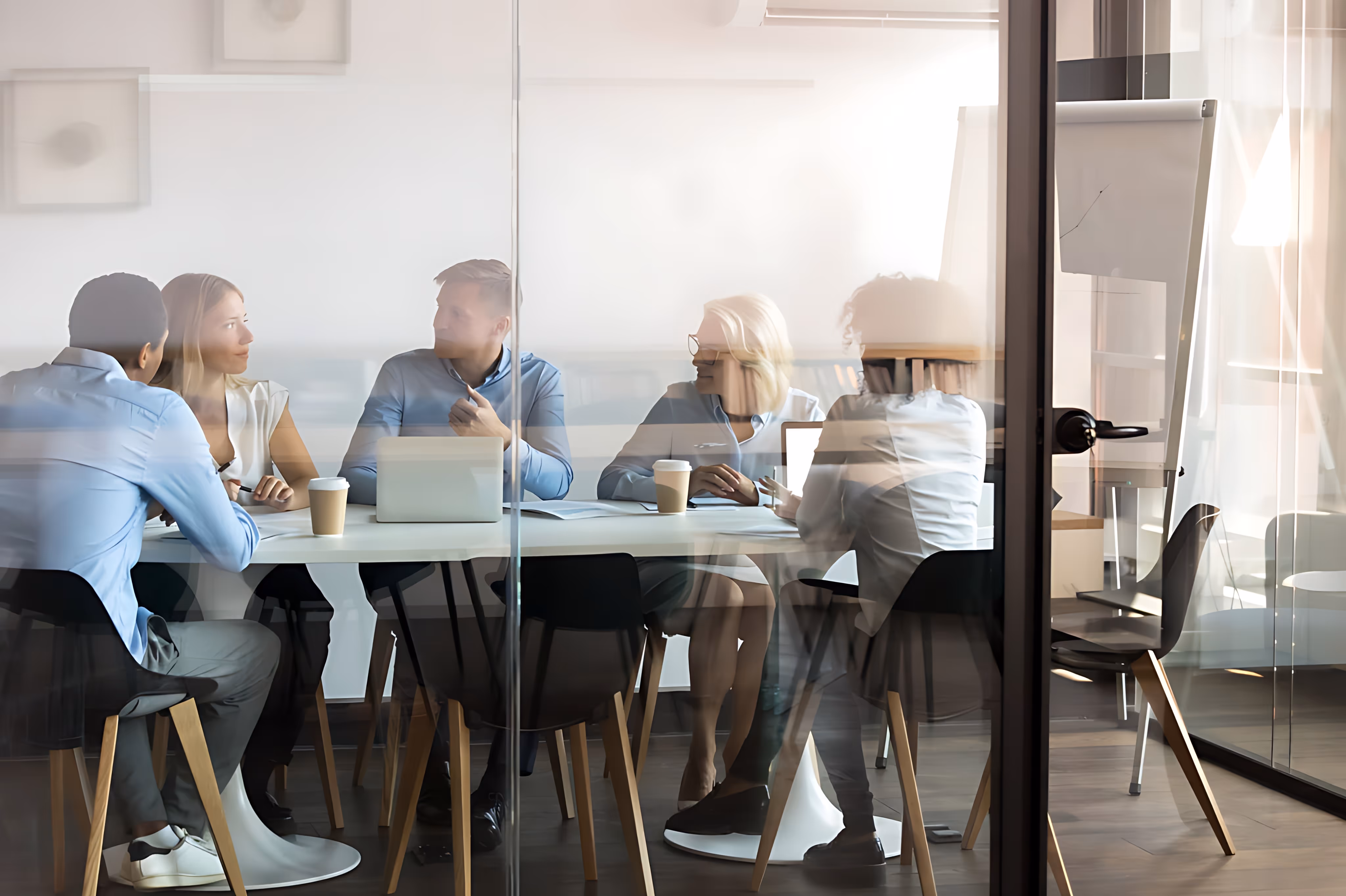 Fünf Personen sitzen in einem Besprechungsraum zusammen und tauschen sich aus
