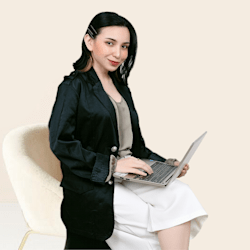 A women sitting on a chair with laptop in her hands posing for camera