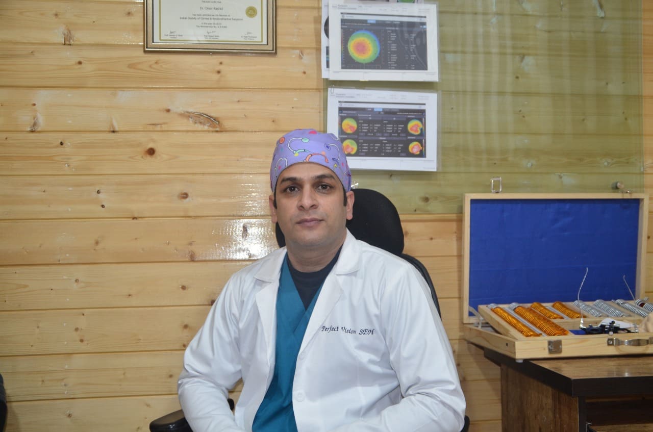 A doctor sitting on chair wearing white coat and smiling 