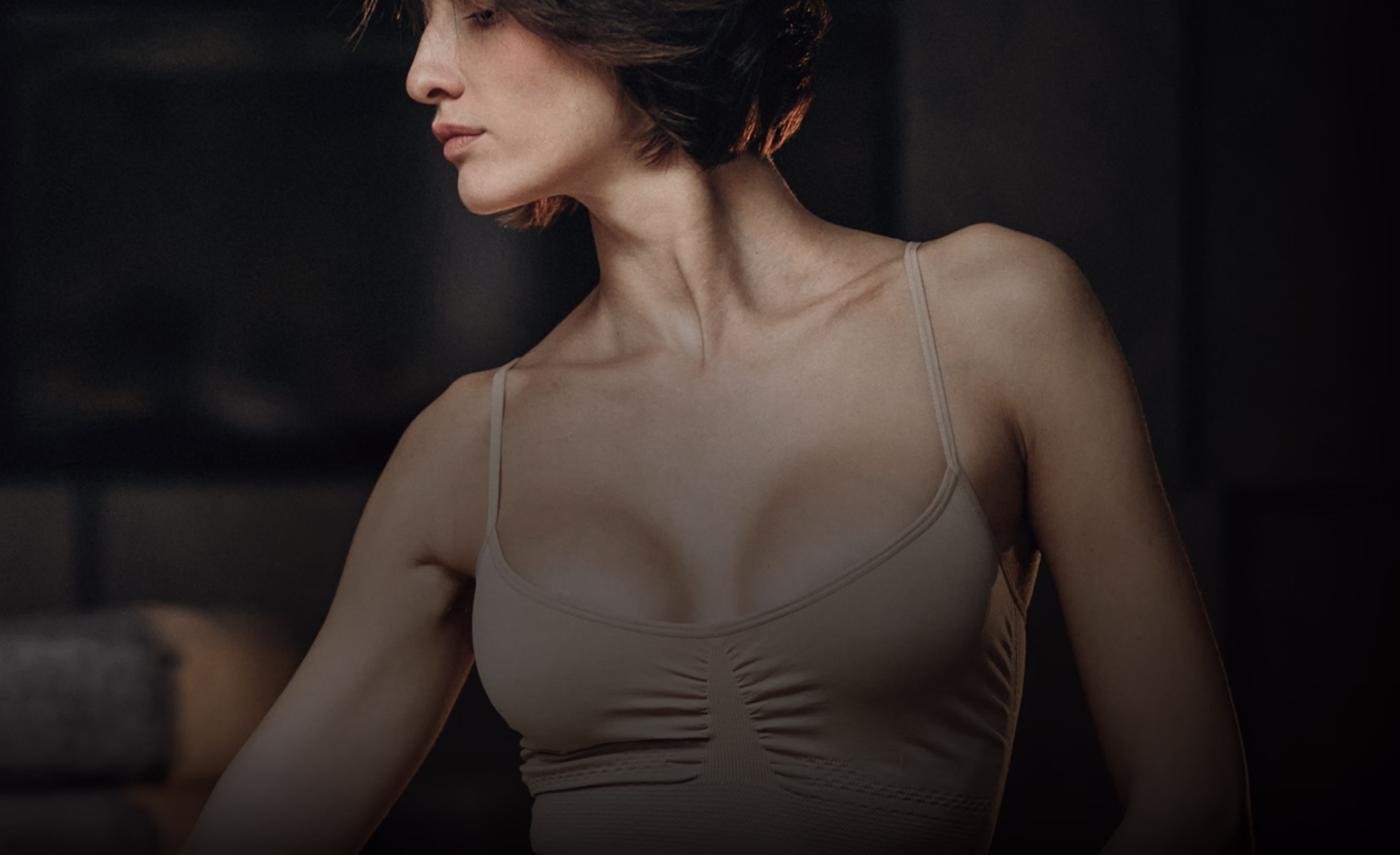A woman wearing a light-colored tank top with a fitted design, showing her shoulder and neck profile.