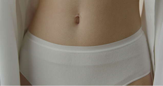 A close-up view of a woman's midsection showing her skin and a white pair of underwear.