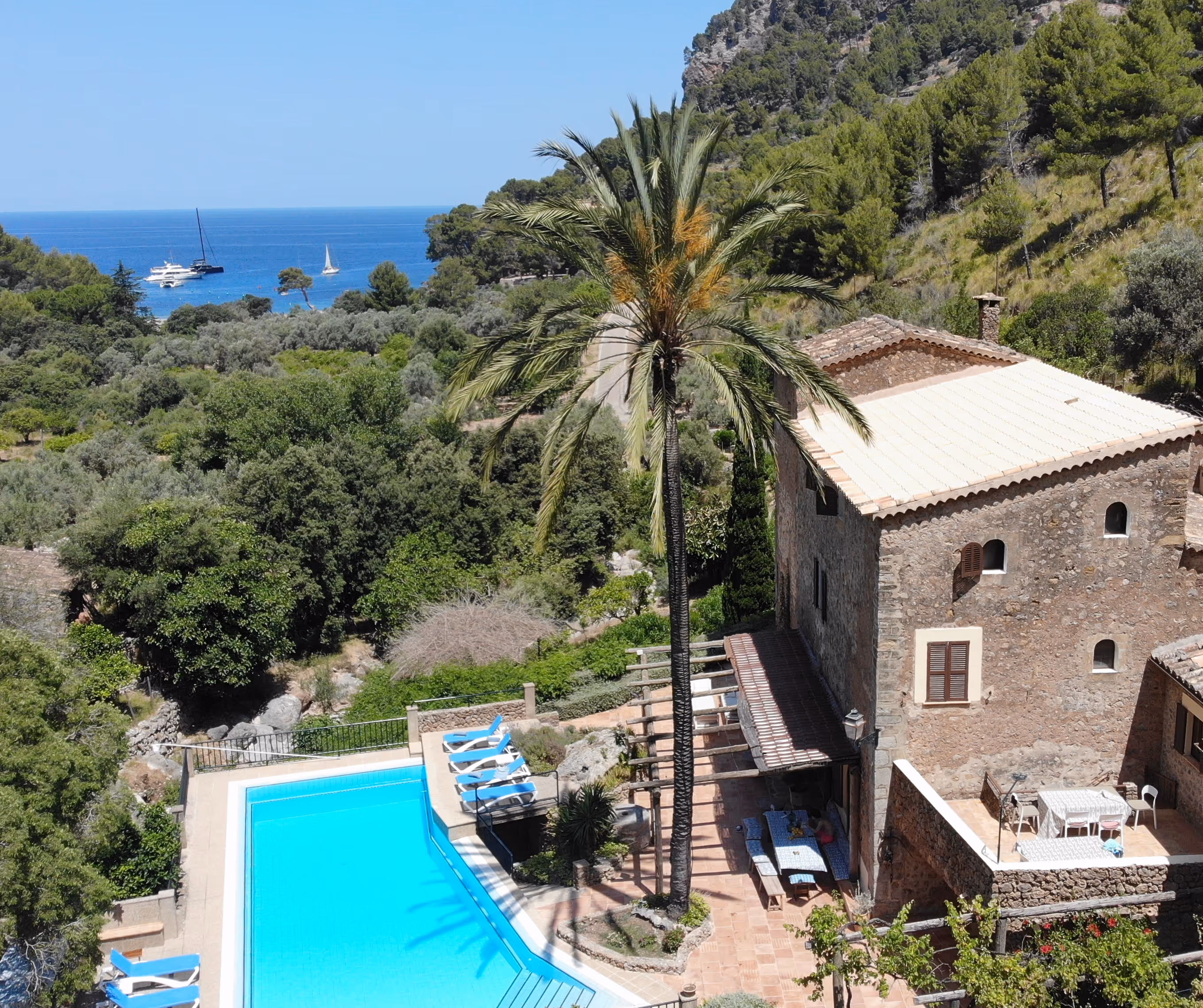 Stone house at Finca Higo with palm trees and an infinity pool overlooking the sea on Mallorca’s rugged coastline.