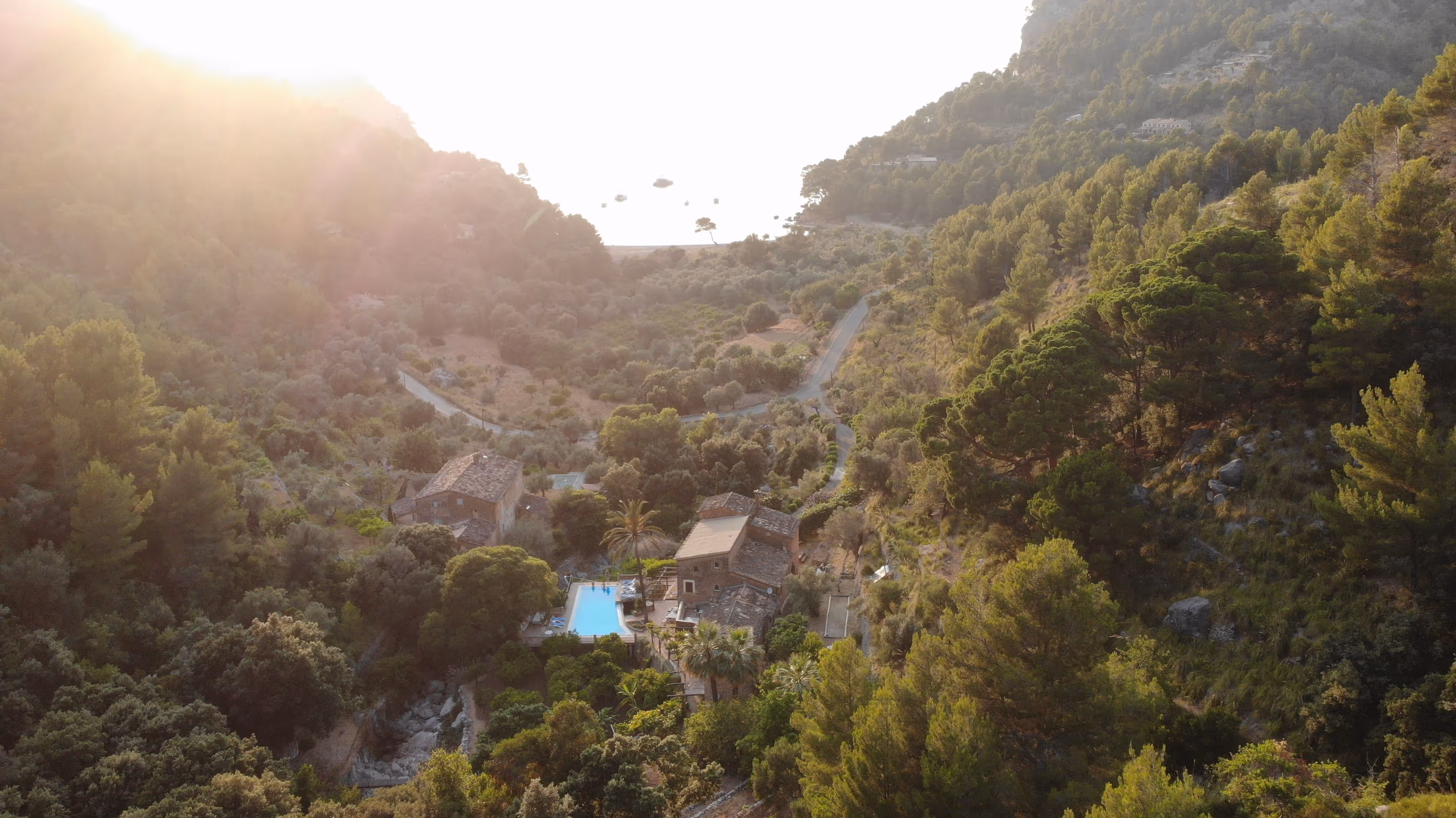 Aerial view of Finca Higo at sunset, nestled in a forested valley with the sea glowing in the background.
