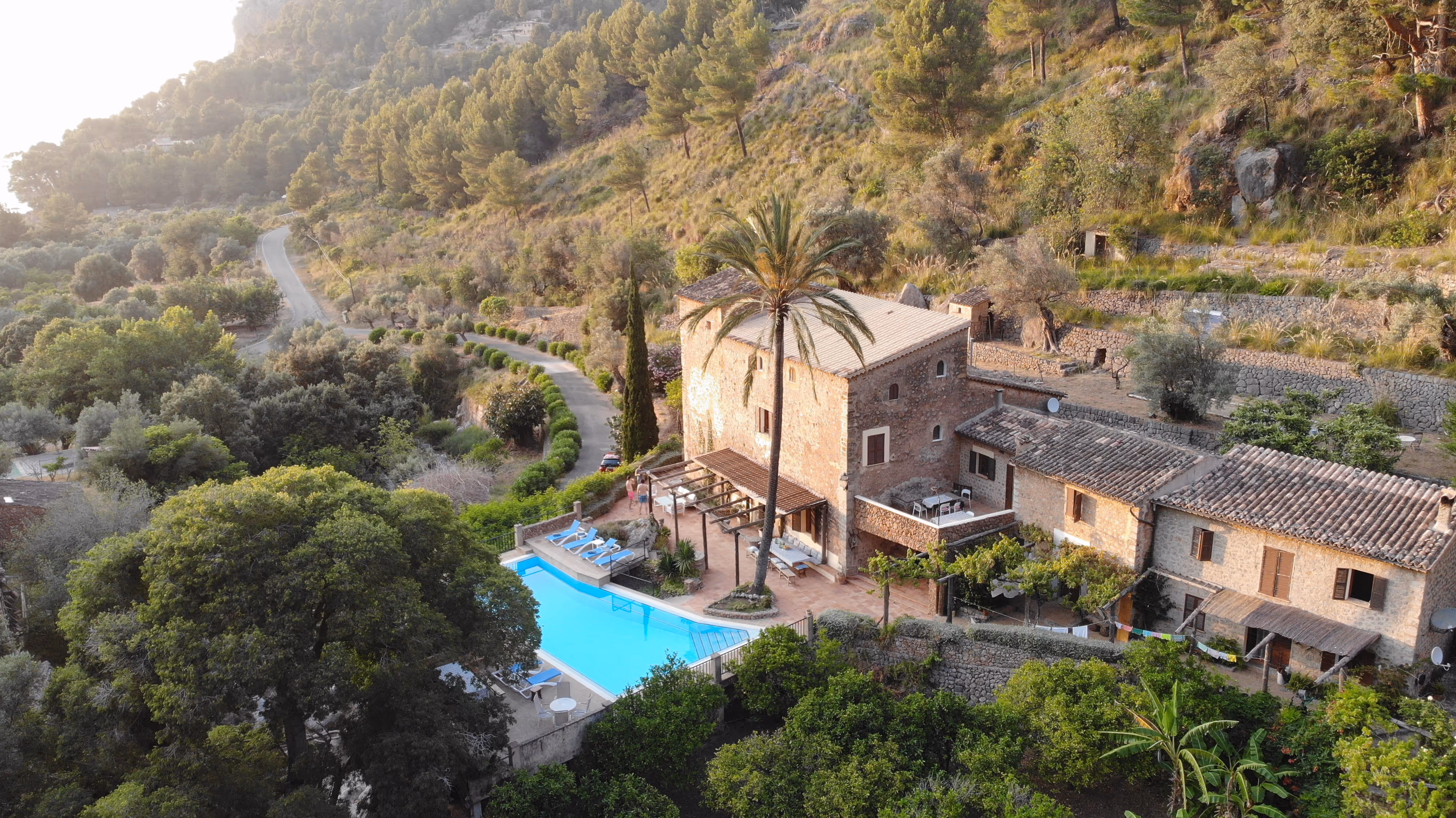 Golden-hour aerial view of Finca Higo’s rustic stone buildings, pool, and surrounding terraces nestled in the hills.