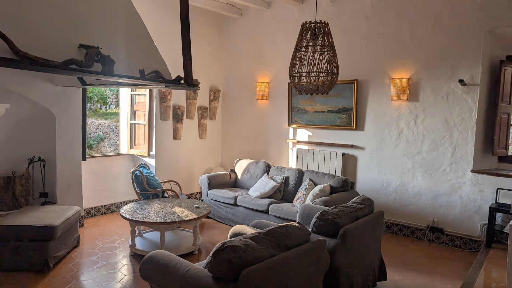 Cozy living room with a fireplace, cushioned sofas, and rustic décor in a traditional stone house at Finca Higo.