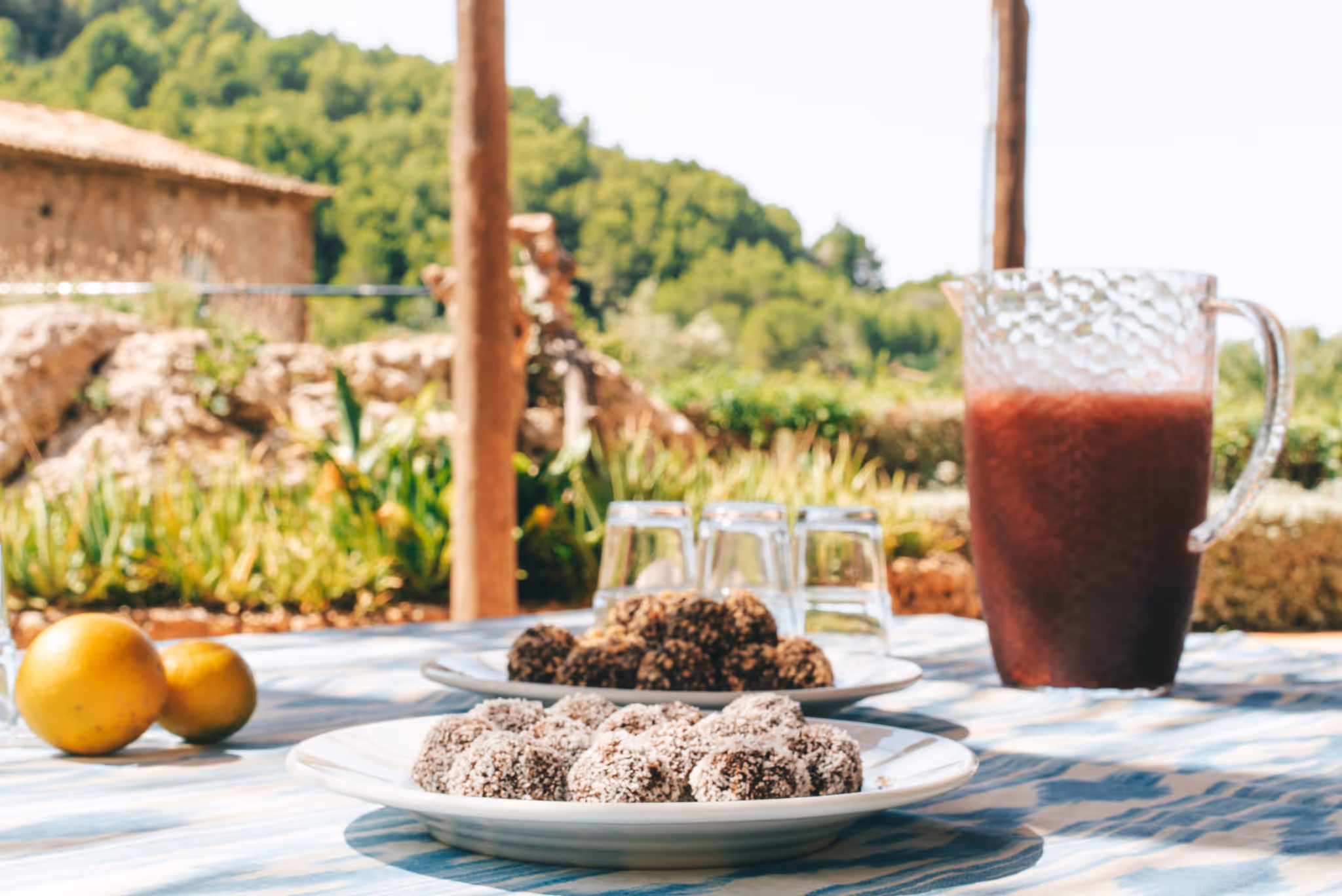 Small afternoon snack with energy bites and a smoothie served on a table in a Mediterranean garden.
