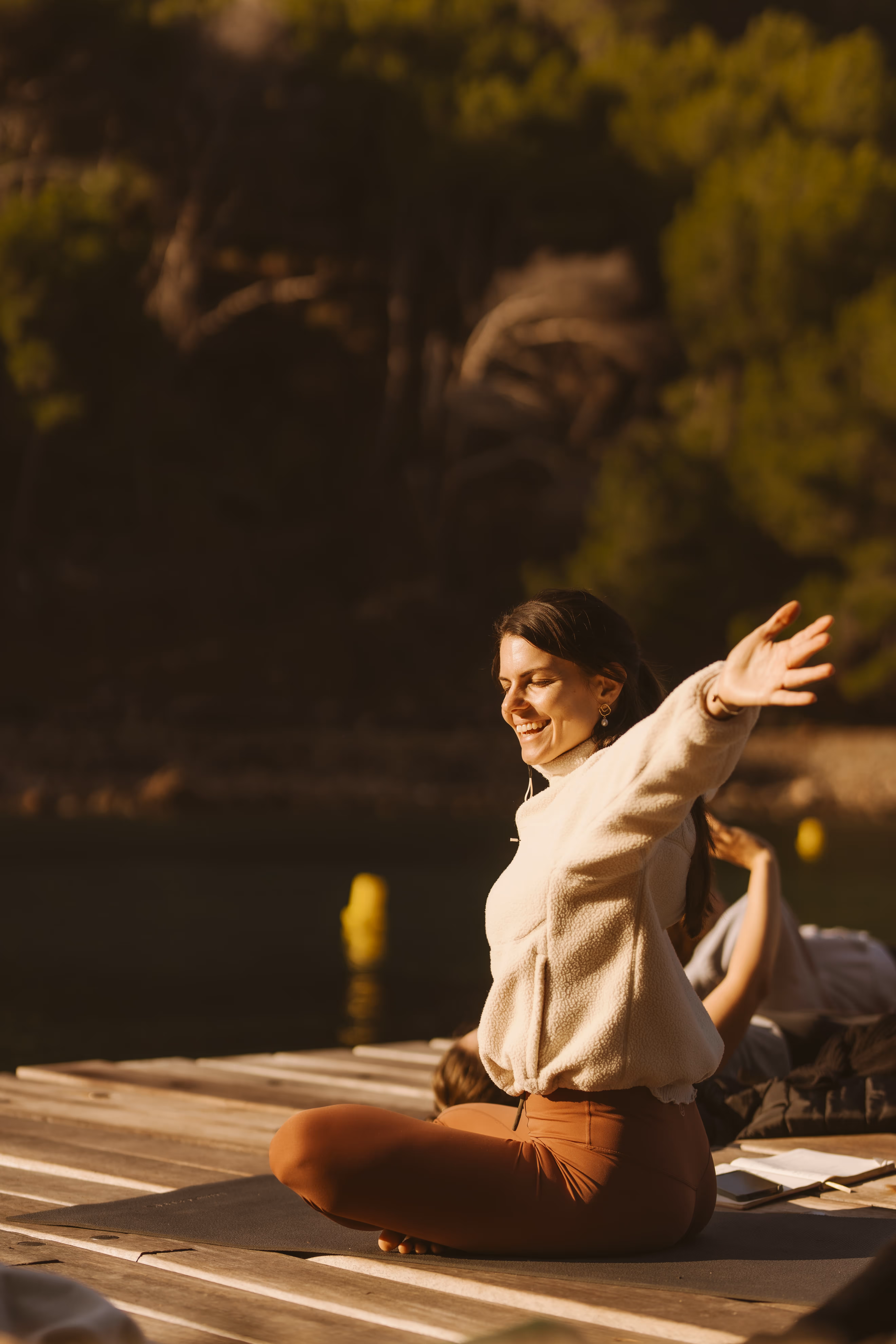 Woman greeting the sun on a yoga mat on the pier of Cala Tuent.