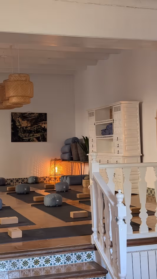 Indoor yoga room at Finca Higo in Mallorca with dim lighting, yoga mats, cushions and wooden blocks.