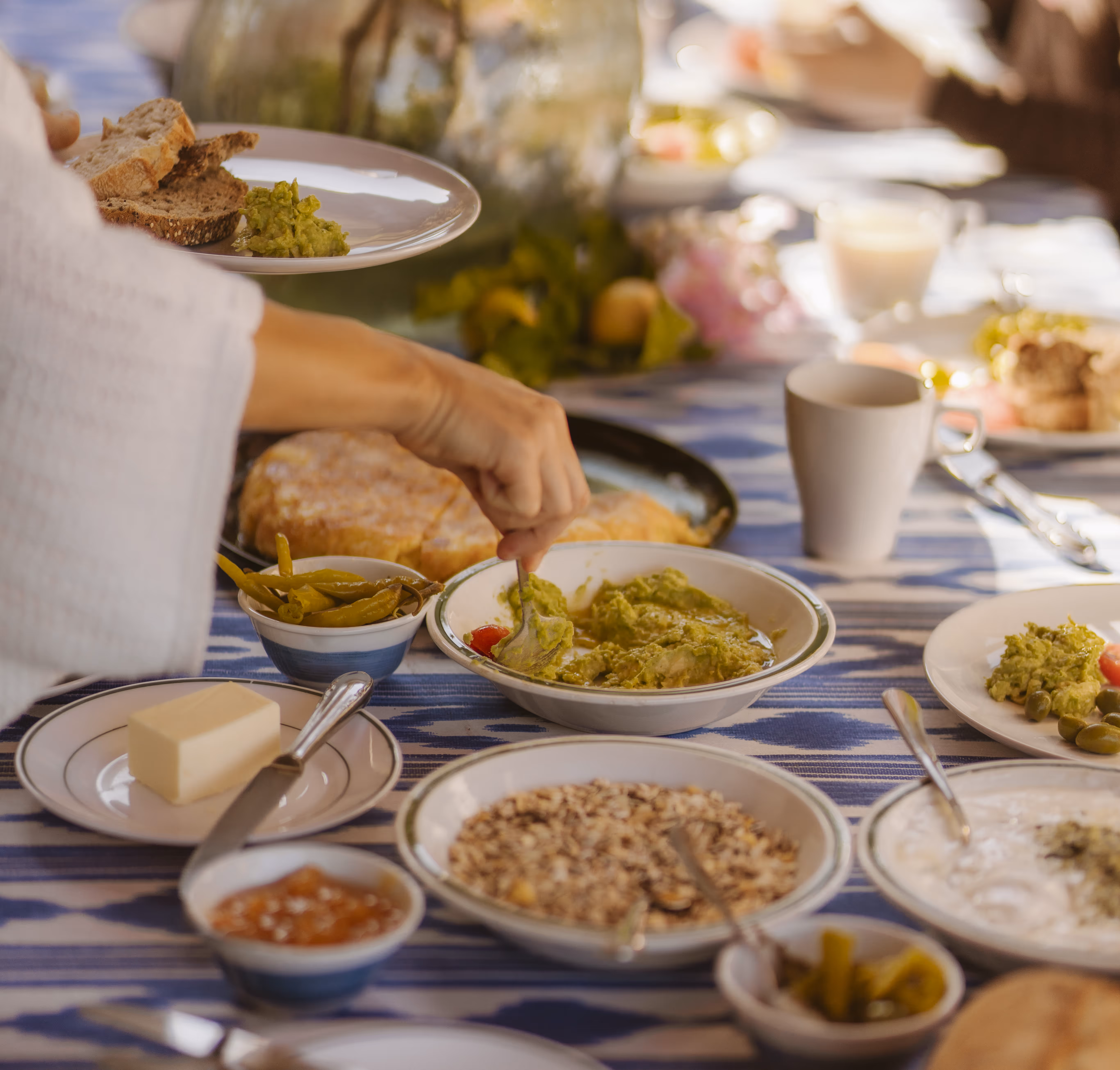 Shared breakfast table with homemade spreads, bread, and fresh dishes at a retreat setting.