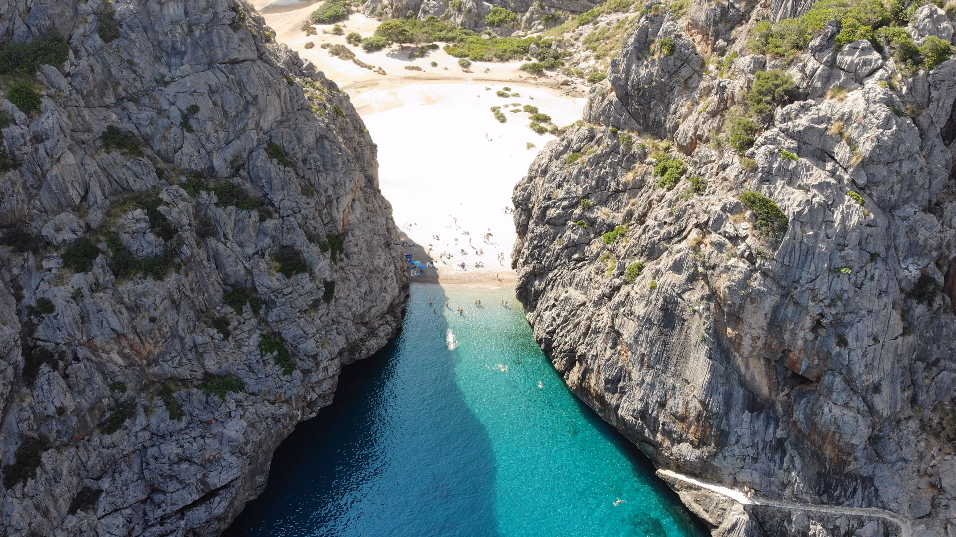 erial view of Sa Calobra beach in Mallorca, with turquoise water between steep rocky cliffs.