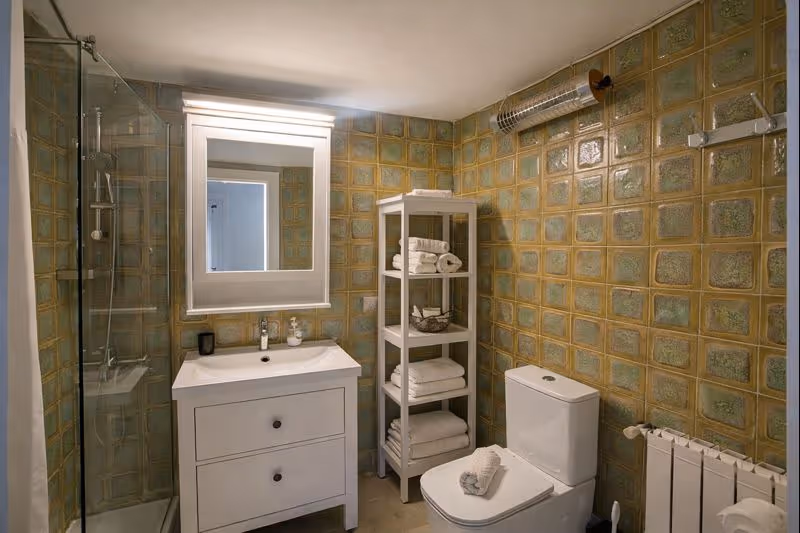 Well-equipped bathroom with a shower, sink, mirror, and tiled walls.